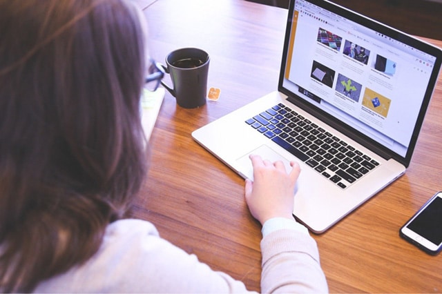 Frau mit Laptop am Tisch beschreibt Service Angebot Webdesign